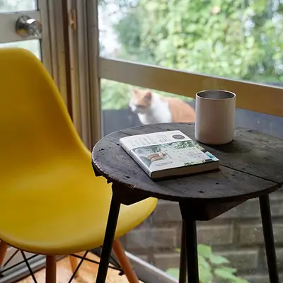 温かい飲み物と本がテーブルの上に乗った、レトロなカフェ席のスライド写真